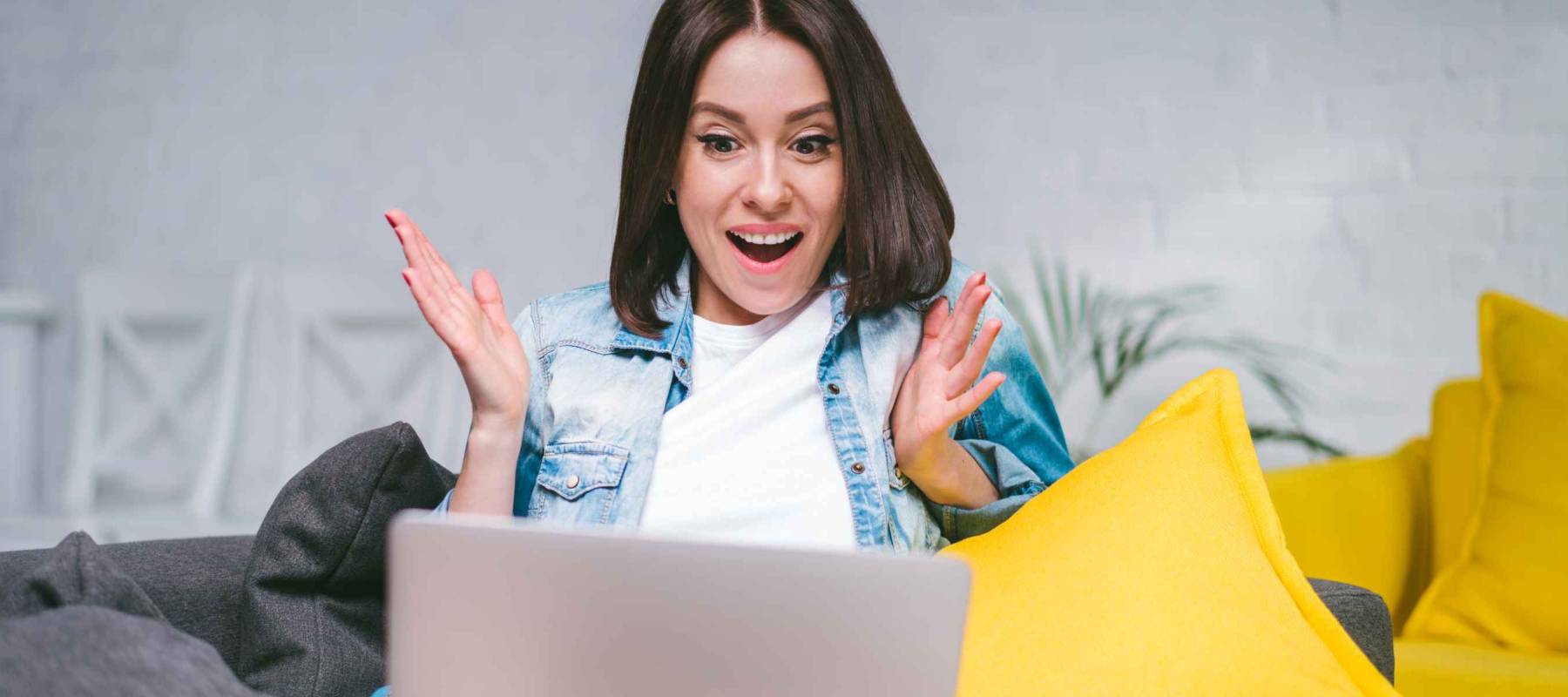 Woman sitting on sofa with astonished mouth open face expression unable to believe, surprised, celebrating money win