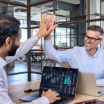 Two happy successful excited diverse traders investors giving high five celebrating successful stock exchange trading deal