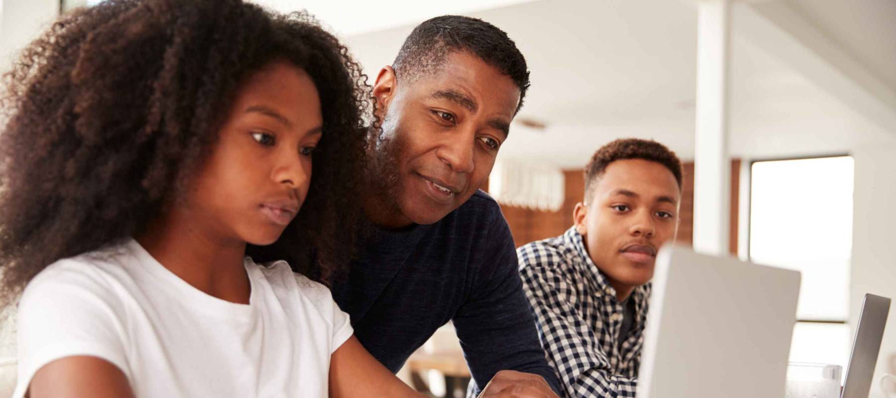 Middle aged black dad helping his teen kids with homework, low angle, close up