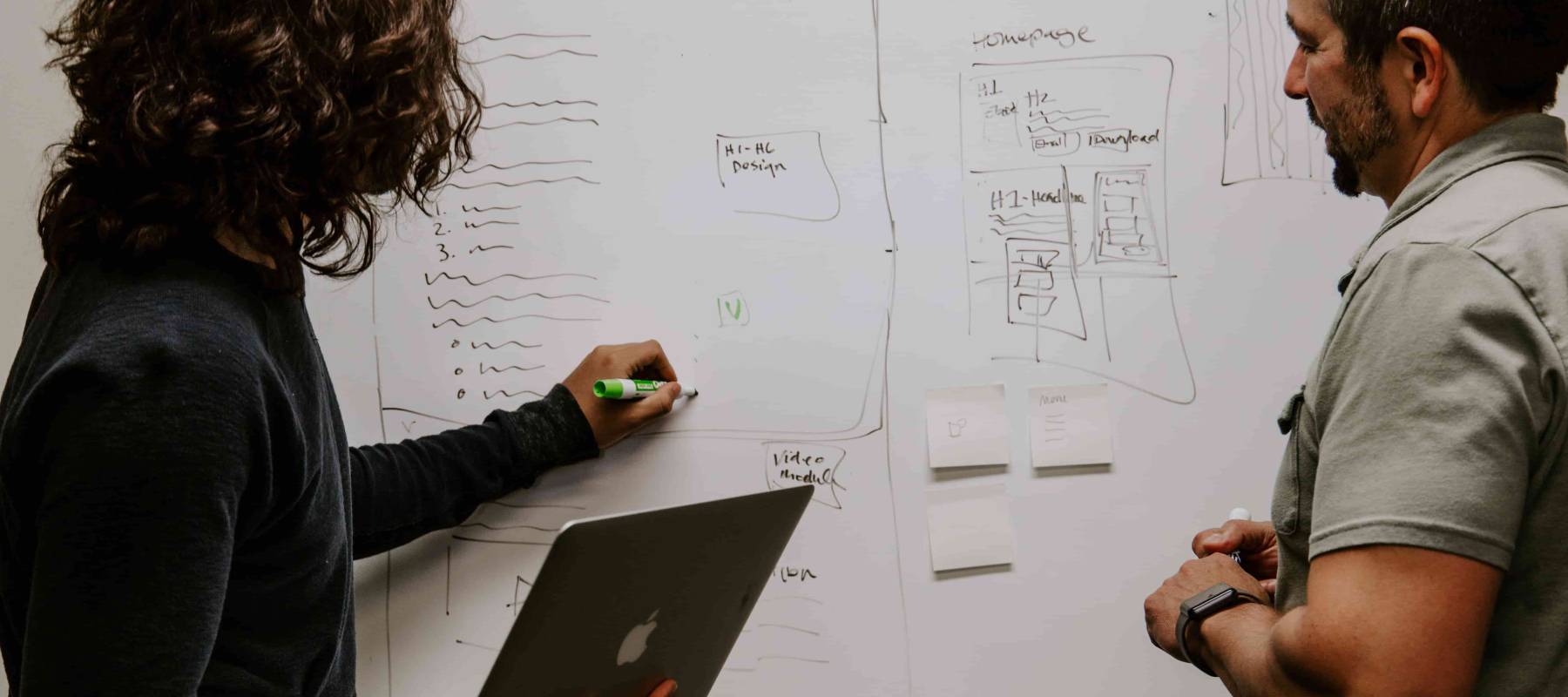 two people writing on white board discussing goals