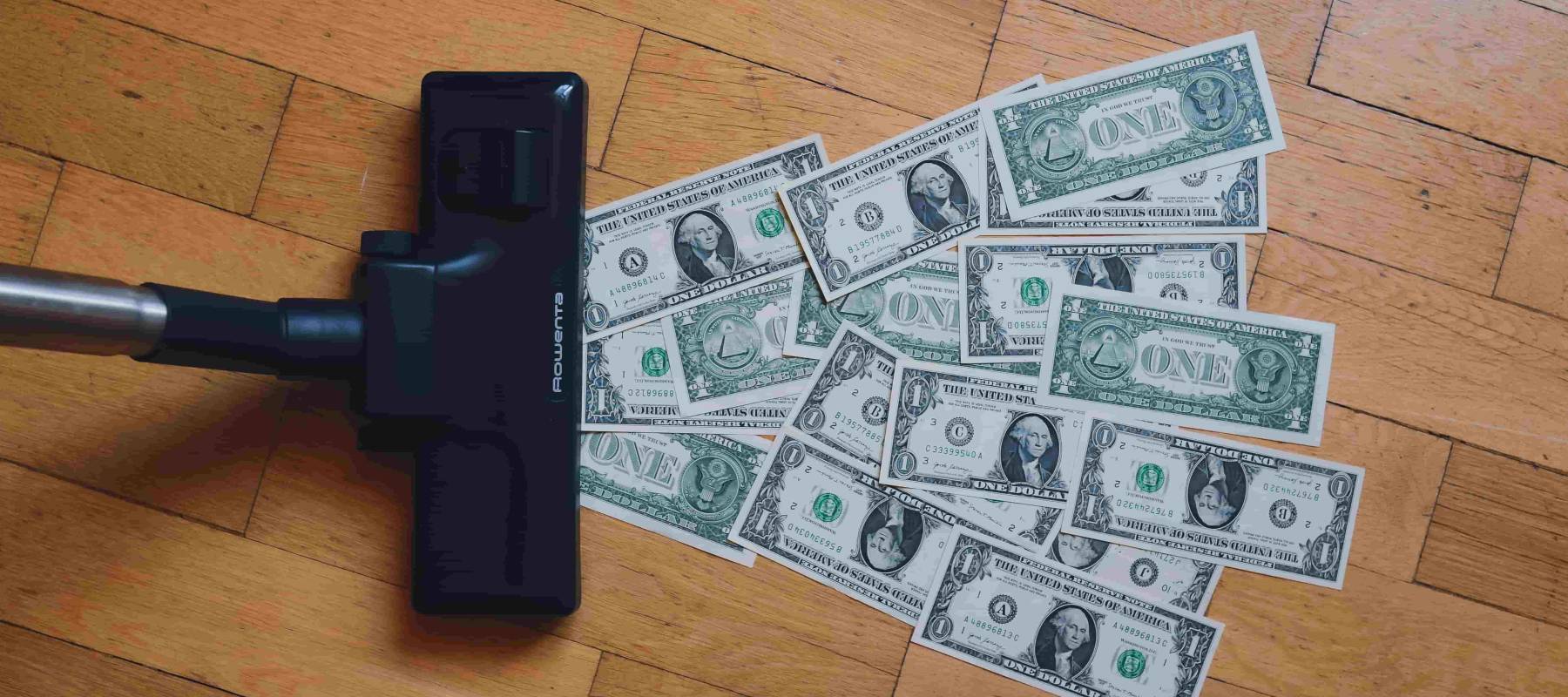 vaccuum sucking up american dollar bills from hardwood floor