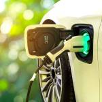 EV Car or Electric car at charging station with the power cable supply plugged in on blurred nature with soft light background. Eco-friendly alternative energy concept