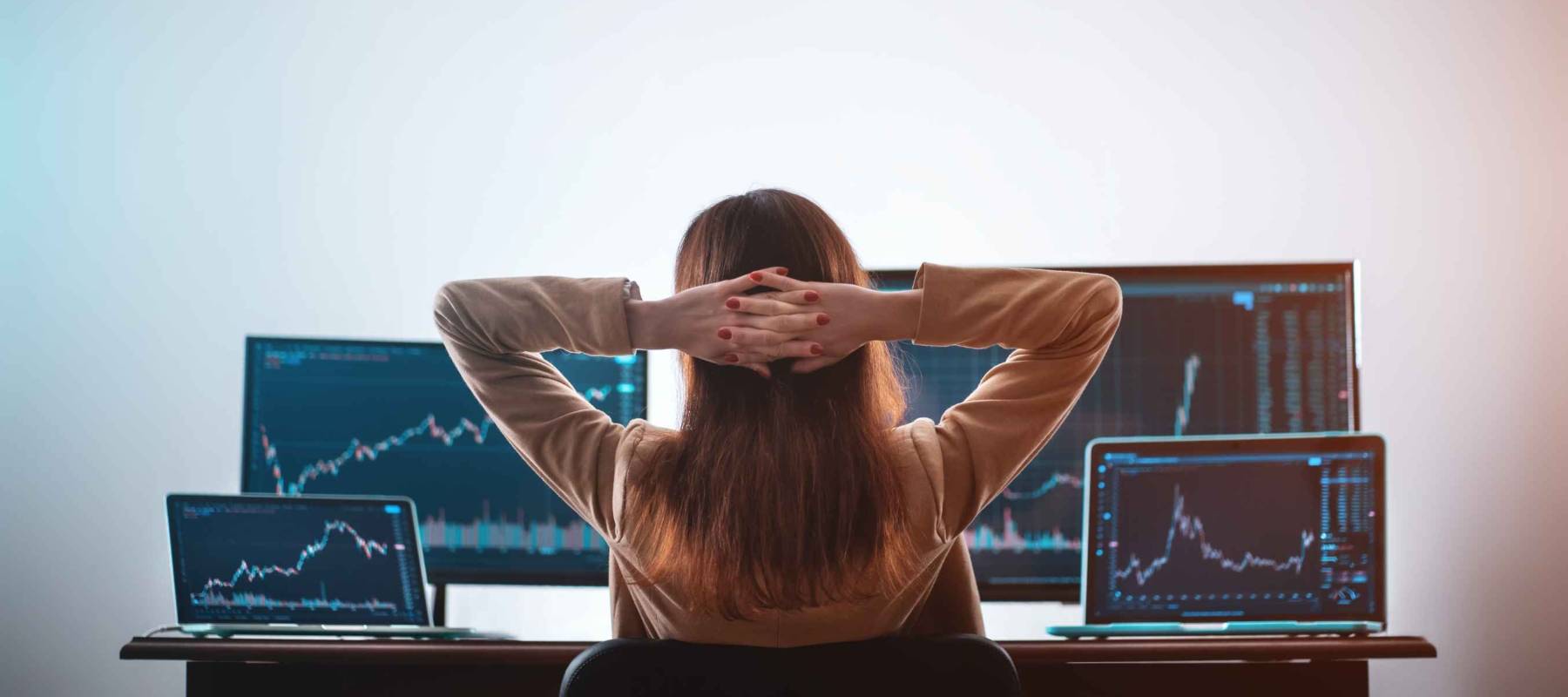 back view of female crypto trader resting and looking at monitor stock exchange