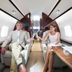 couple clinking champagne glasses smiling on private jet