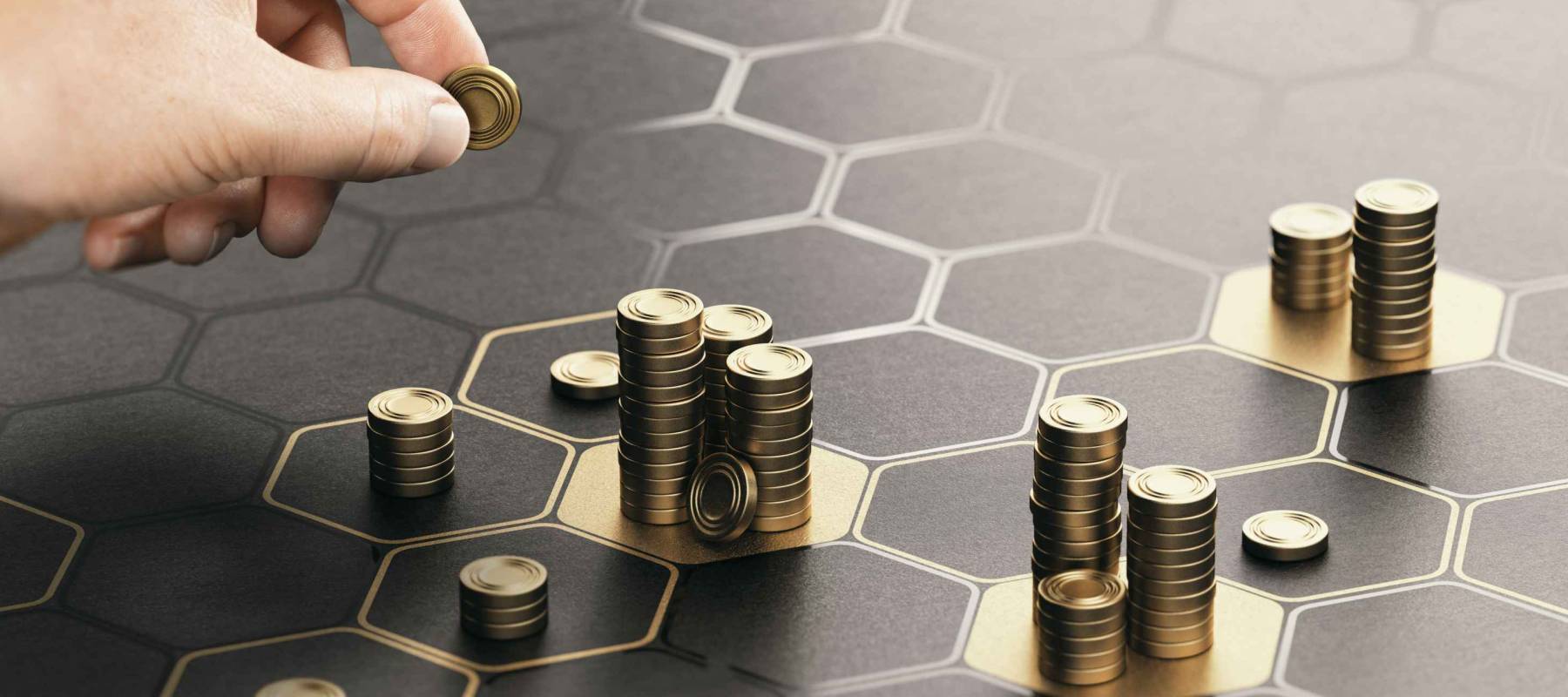 Human hand stacking coins over a black background.