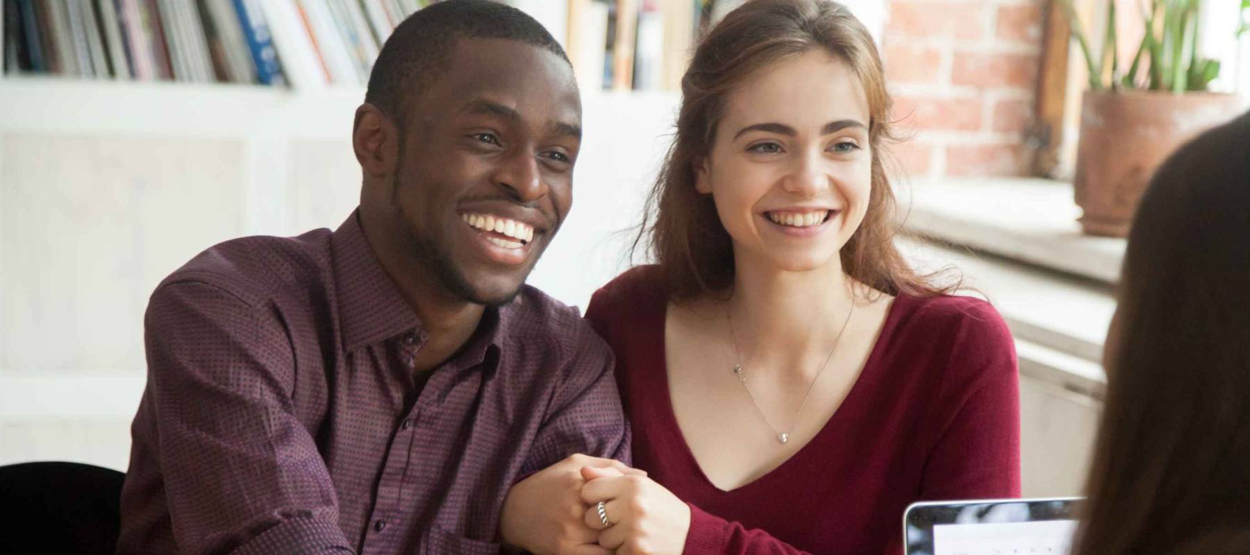 Smiling multiracial couple customers shaking hands with mortgage broker
