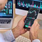 Crypto trader investor broker using smartphone app analyzing financial data stock market price on cell phone