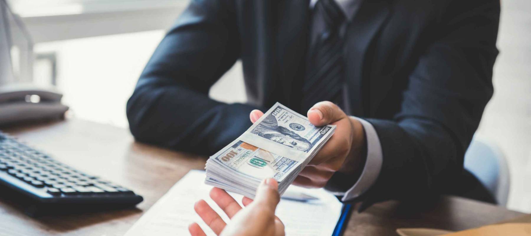 Businessman giving money to his partner while making contract - bribery and corruption concepts