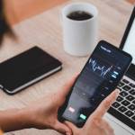 Trader business woman using trading stock market exchange app - Bitcoin, global economy concept - Focus on hands holding mobile phone