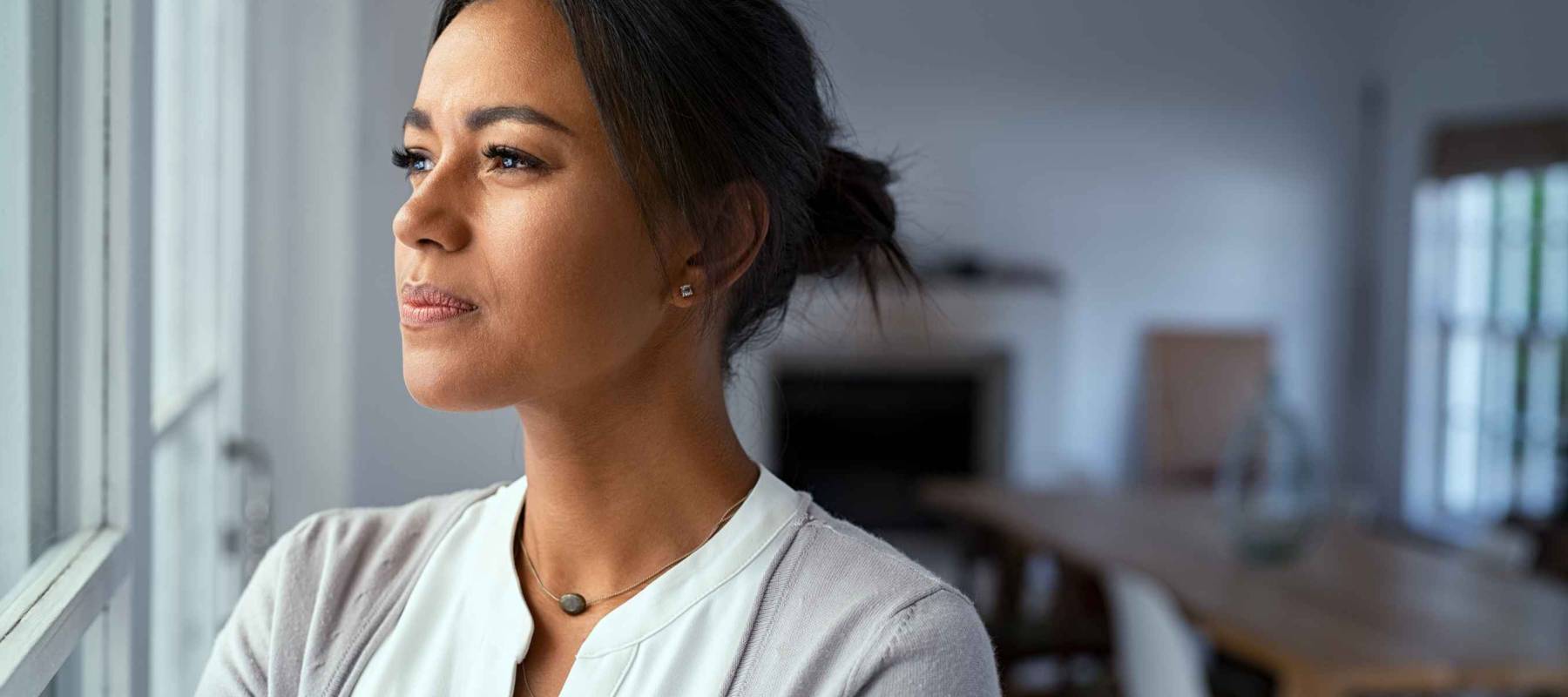 Mature african woman looking outside window with uncertainty. T