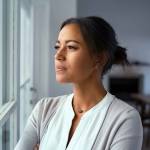 Mature african woman looking outside window with uncertainty. T