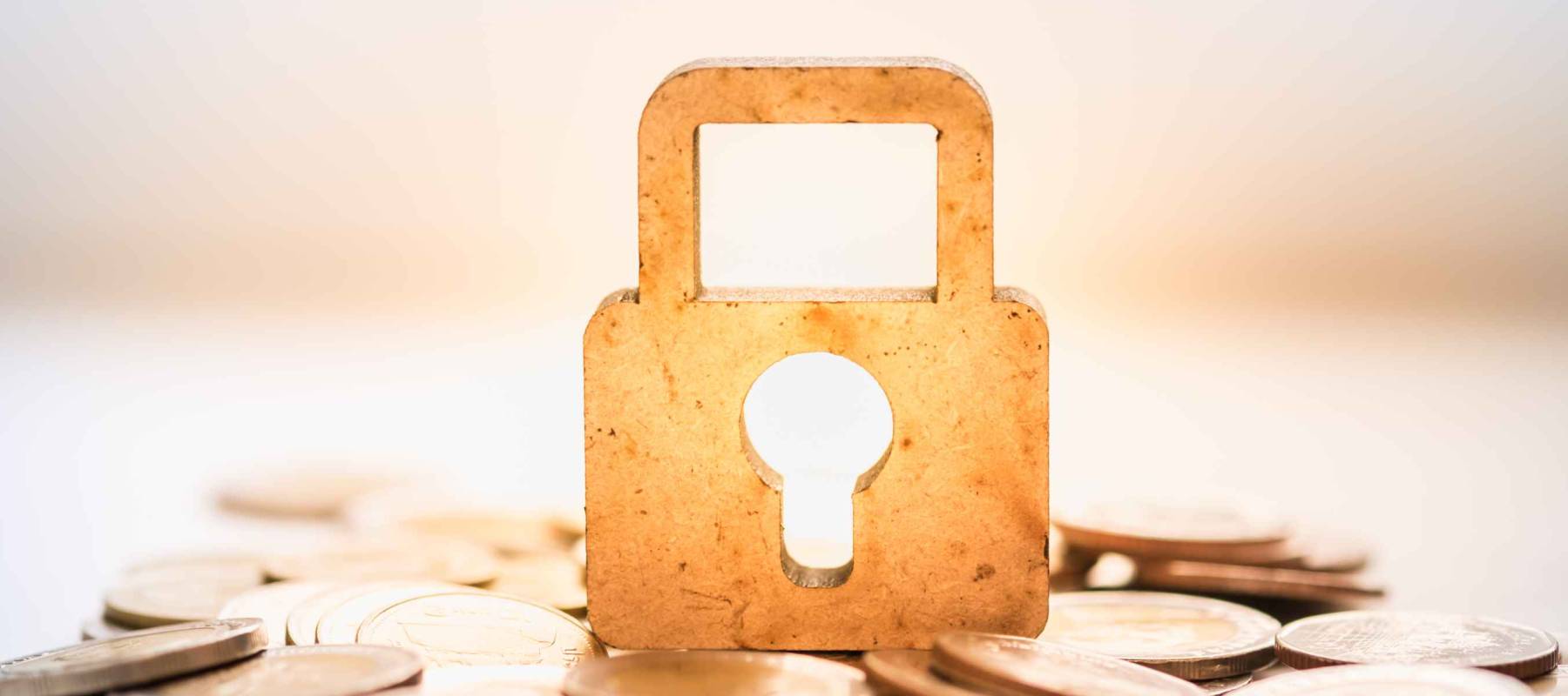 Money and Security Concept. Wooden master key lock icon on pile of coins.