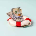 A lifebuoy with banknotes lie on a blue background, the concept of assistance and security in finance