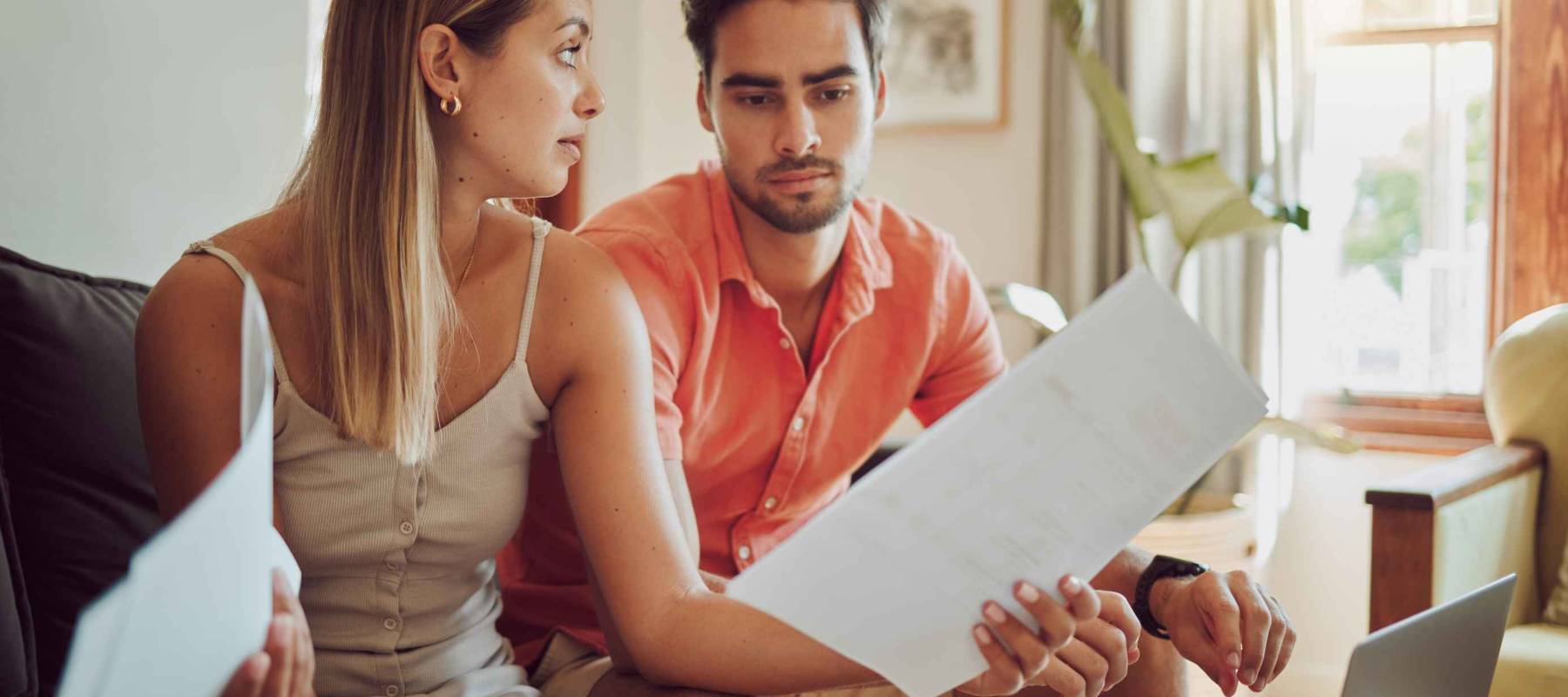 Unhappy, stressed and upset couple paying bills or debt online on with a laptop at home getting angry, planning budget.