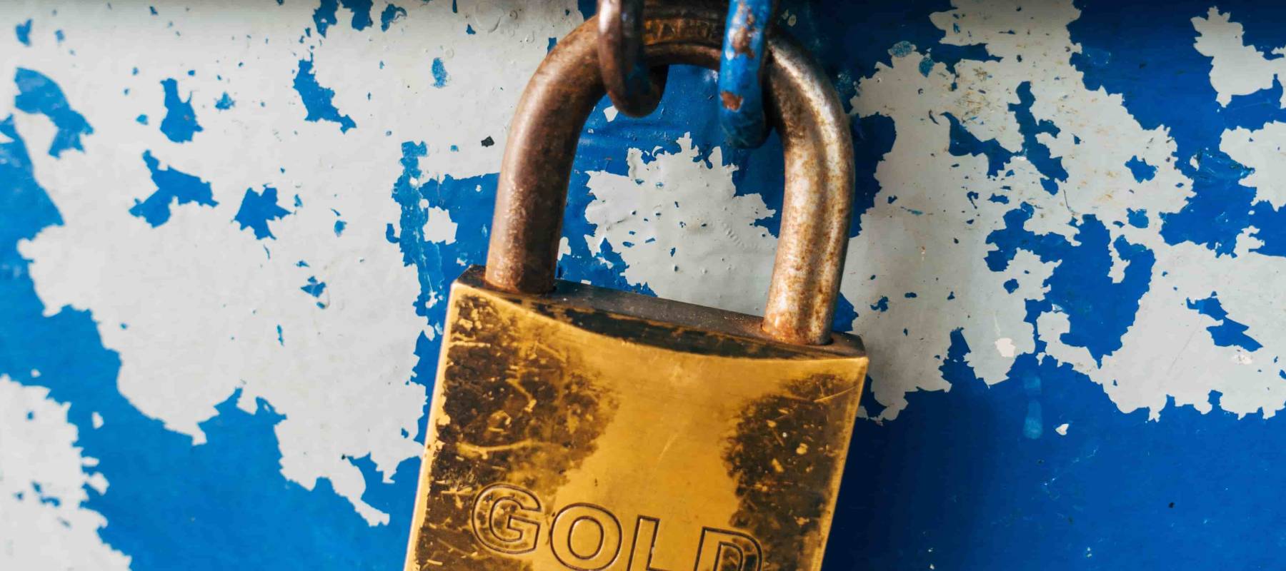 deadbolt lock  with the word gold embossed on it keeps a blue metal bin closed