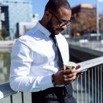 Side view of handsome elegant black man with coffee and phone