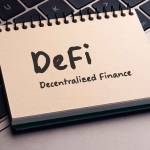 There is note book with the word DeFi (Decentralized Finance) on a laptop. It is an eye-catching image.