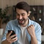 bearded male looking at cell phone after buying solana smiling