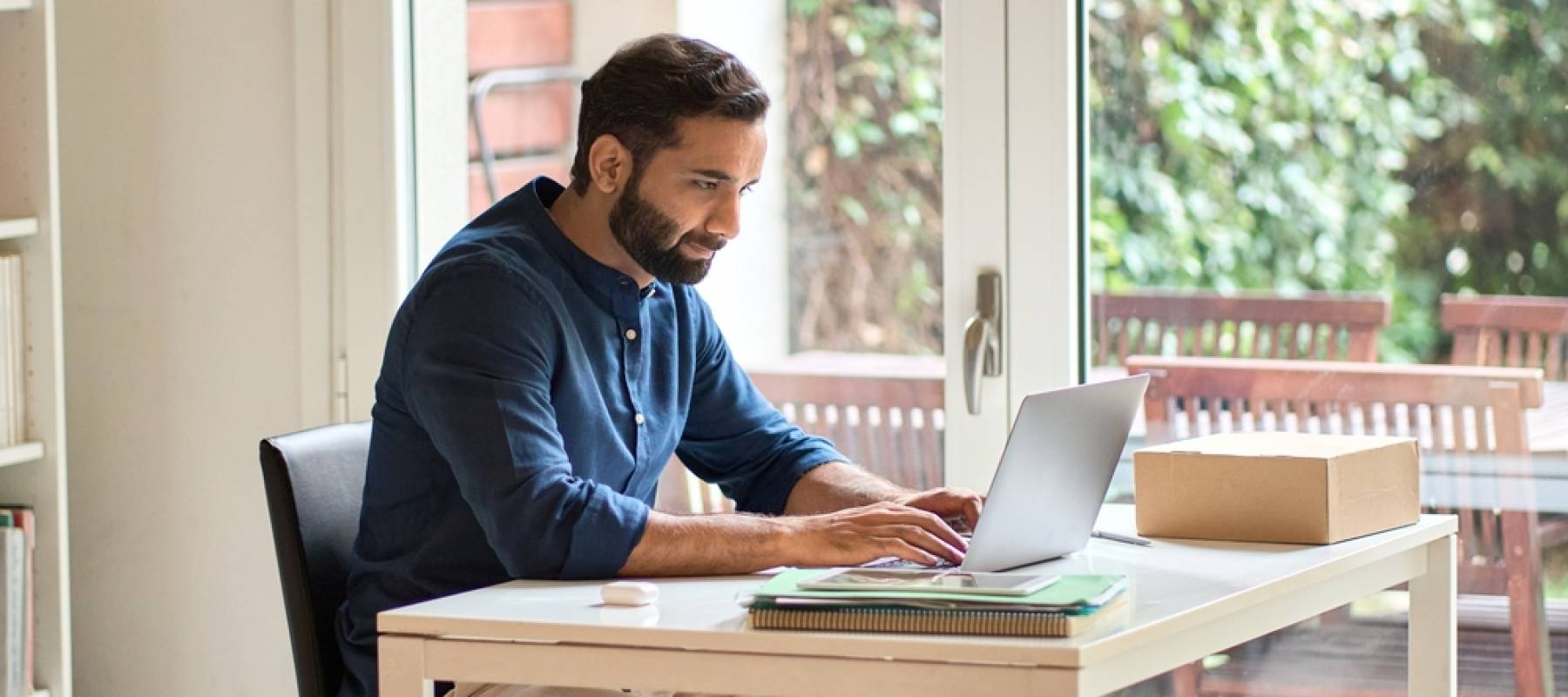 a young bearded man working on his laptop in a home office