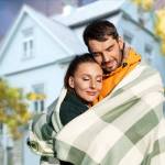 couple embracing wrapped in a blanket in front of a house