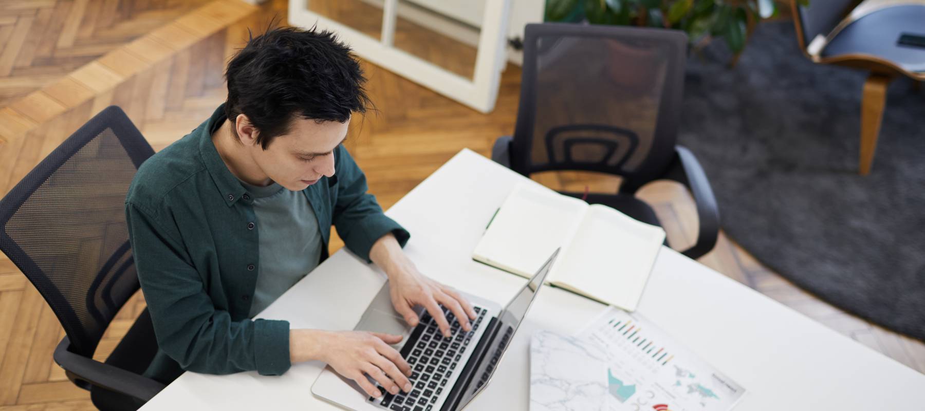 High angle view of businessman sitting at the table and typing on laptop he working online at office