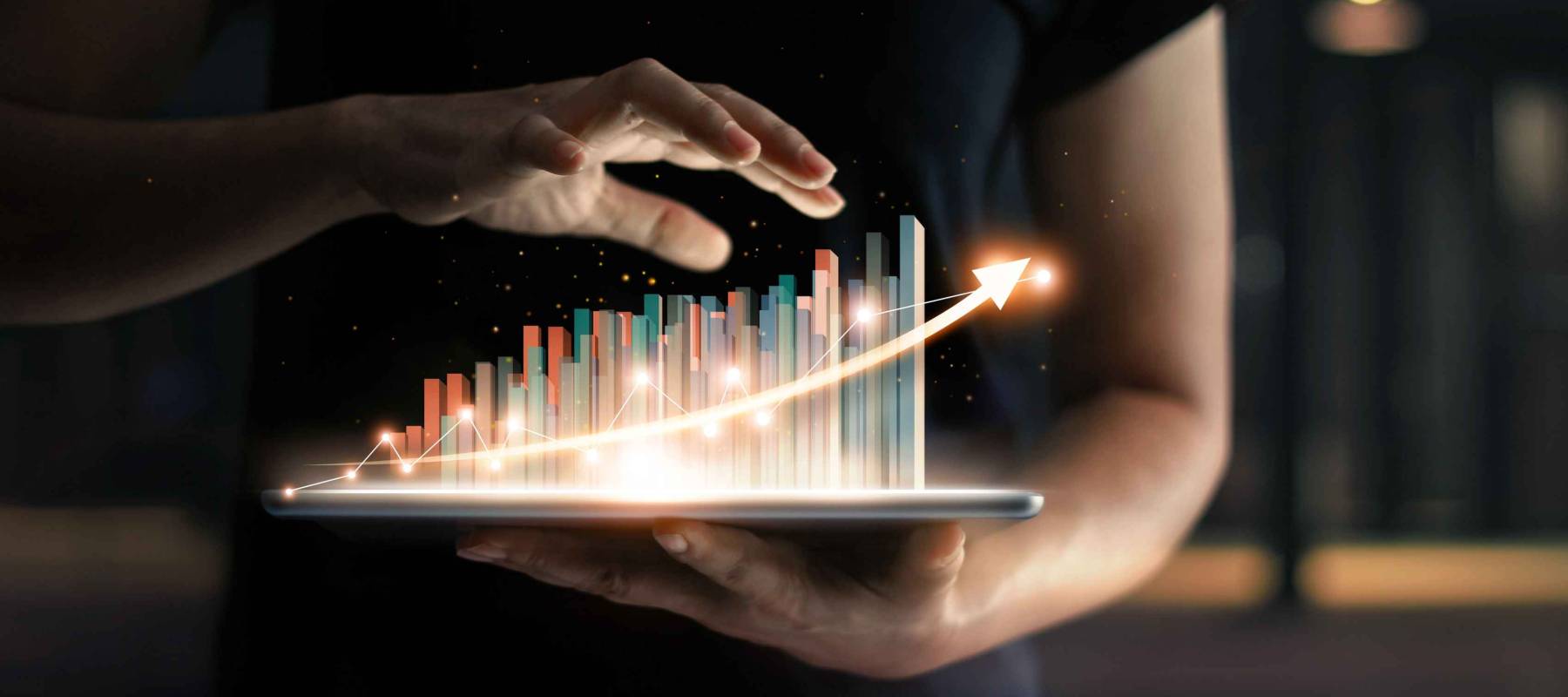 businessman holding tablet and showing a growing virtual hologram of statistics, graph and chart with arrow up on dark background. Stock market. Business growth, planing and strategy concept.