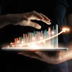 businessman holding tablet and showing a growing virtual hologram of statistics, graph and chart with arrow up on dark background. Stock market. Business growth, planing and strategy concept.