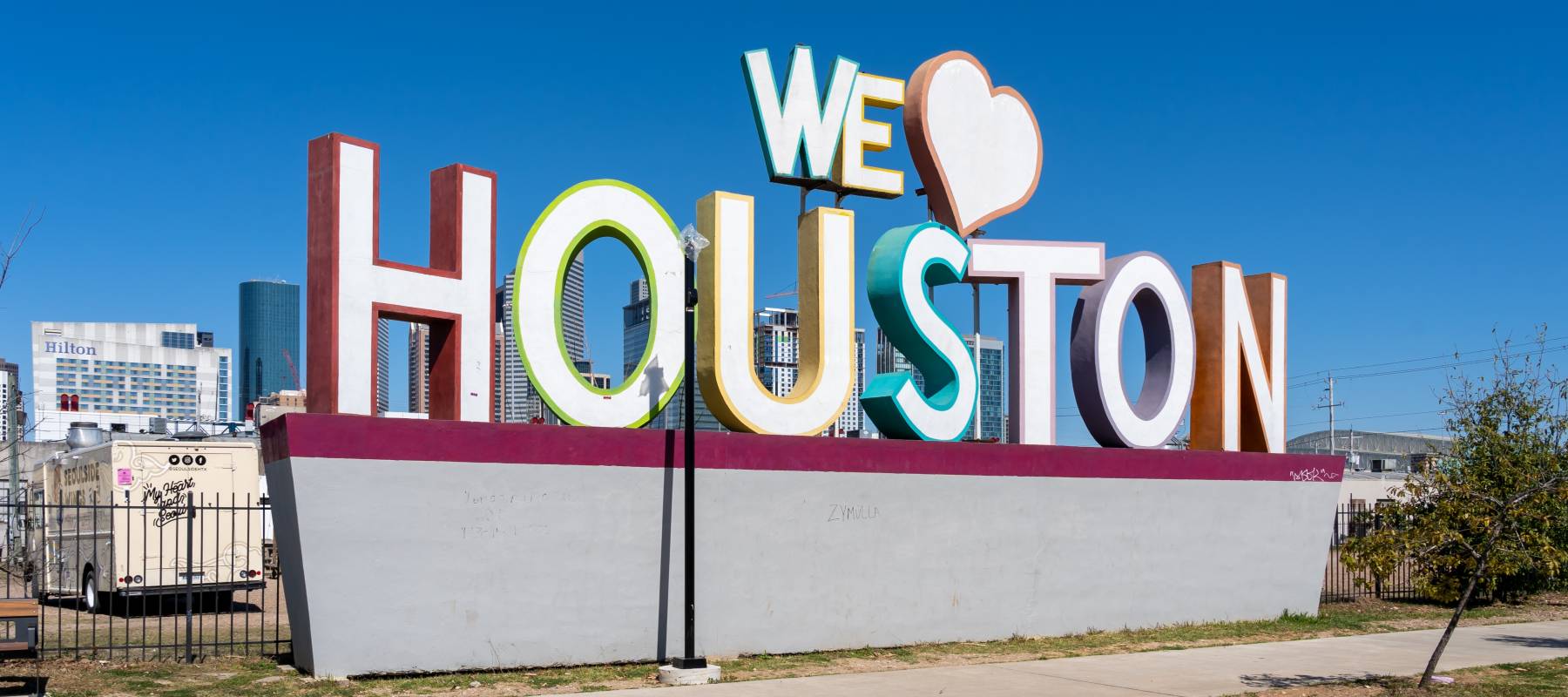 A sign that says ‘We Love Houston’ with Downtown Houston in the background