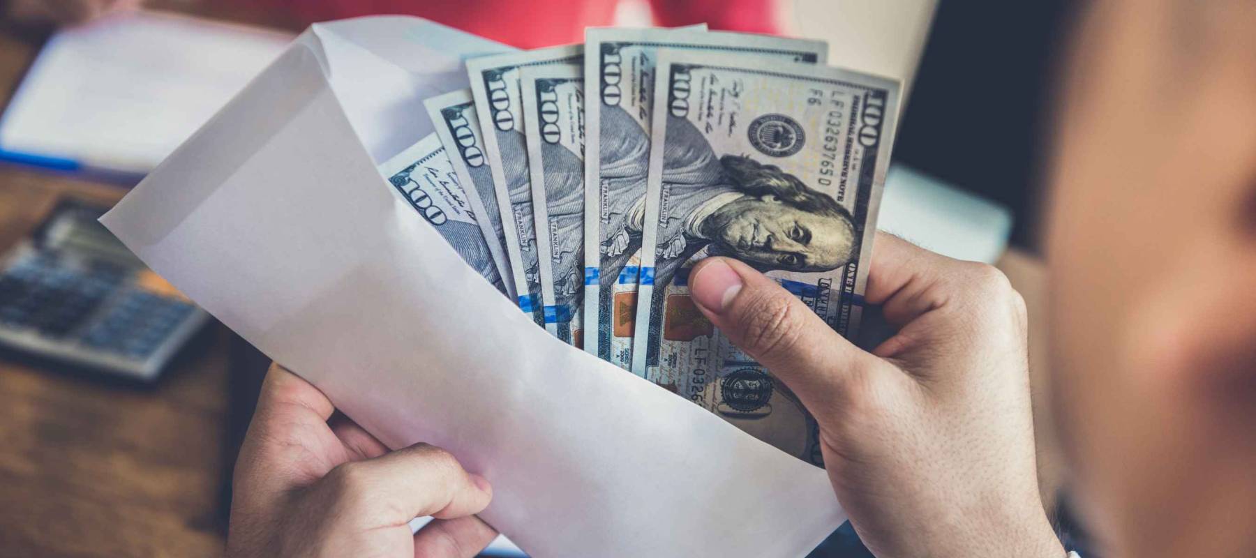 Businessman checking money inside the envelope at his working desk - bribery and corruption concepts