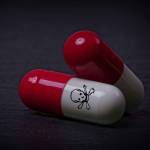 Drug capsules with skull and crossbone on dark stone background.