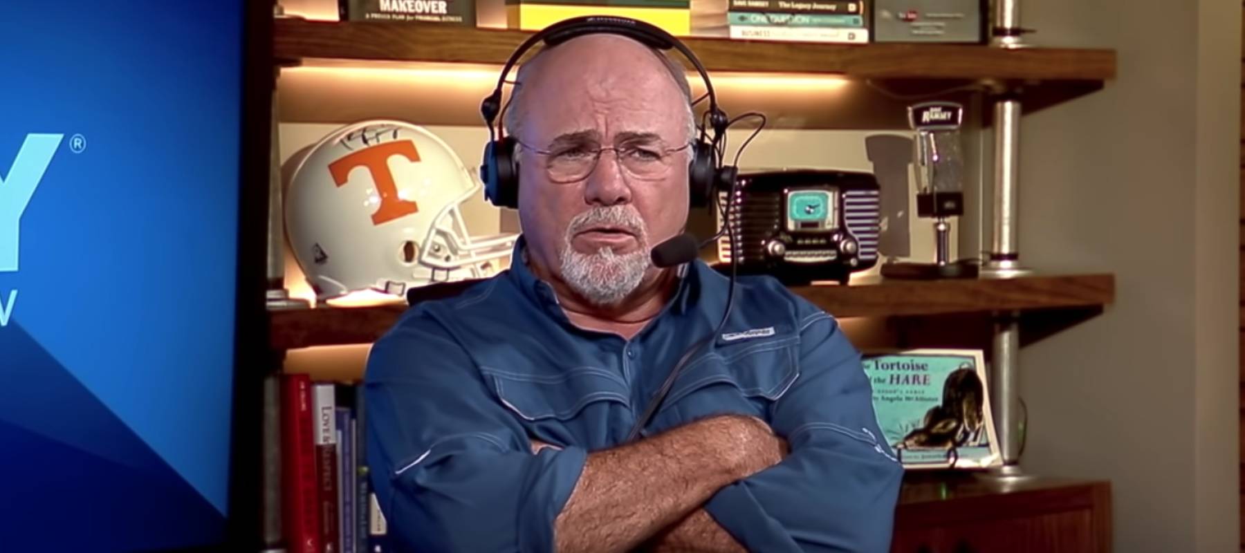 Dave Ramsey sits on set of his show with an incredulous look on his face and his arms crossed.