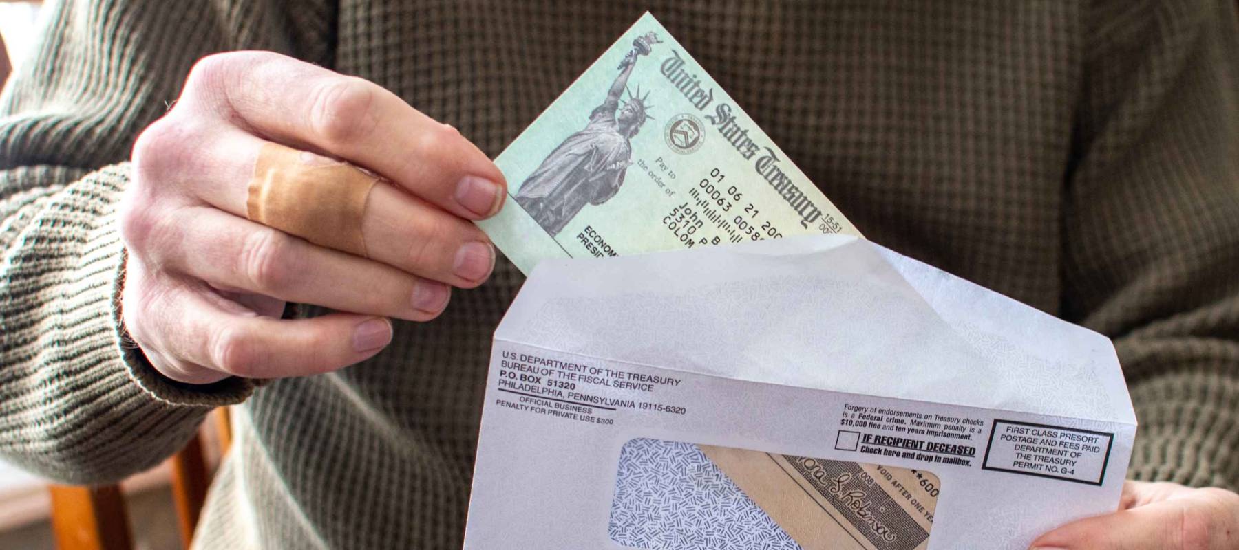 A man's hand holds a letter with a covid aid check from the USA government