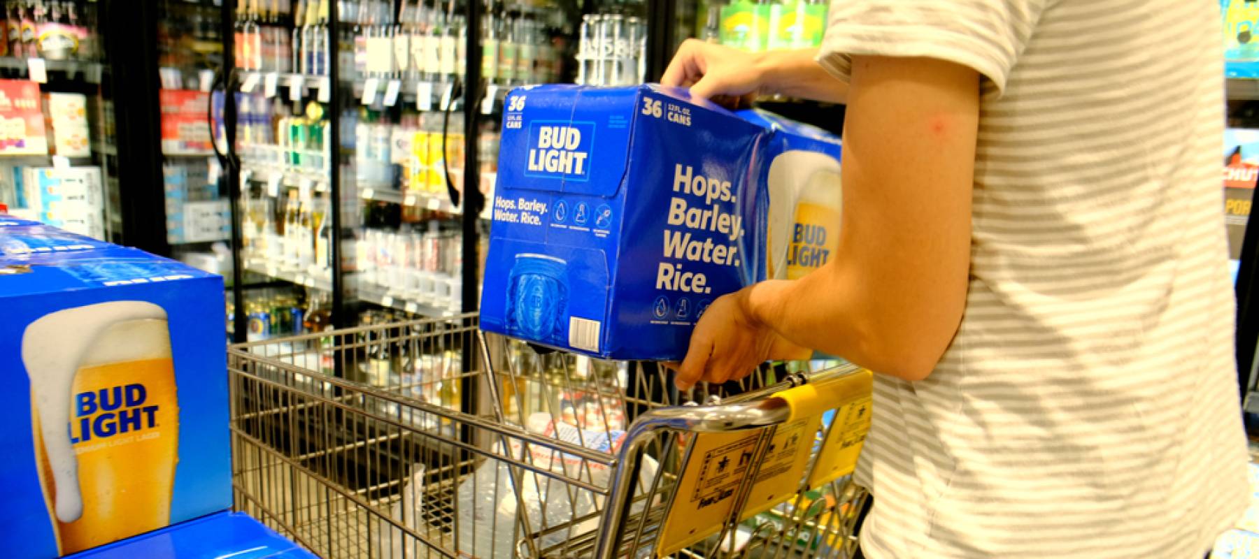 Shopper grabbing a Box of Bud Light brand beer in a supermarket.