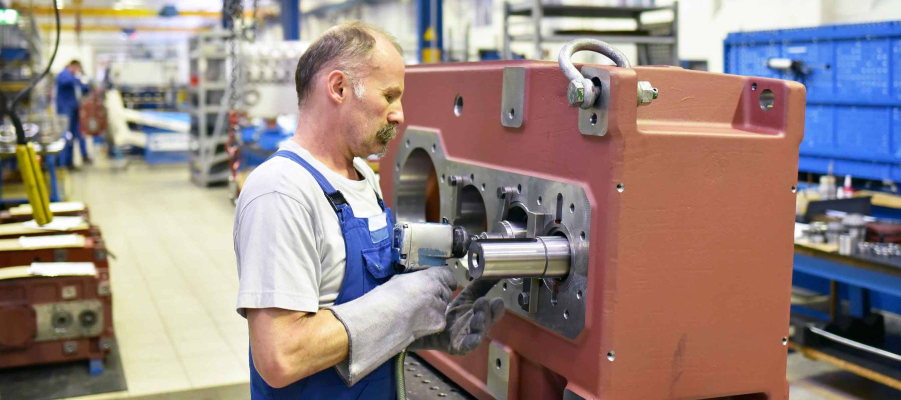 older worker in mechanical engineering - industrial factory for the production of steel gearboxes