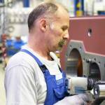 older worker in mechanical engineering - industrial factory for the production of steel gearboxes