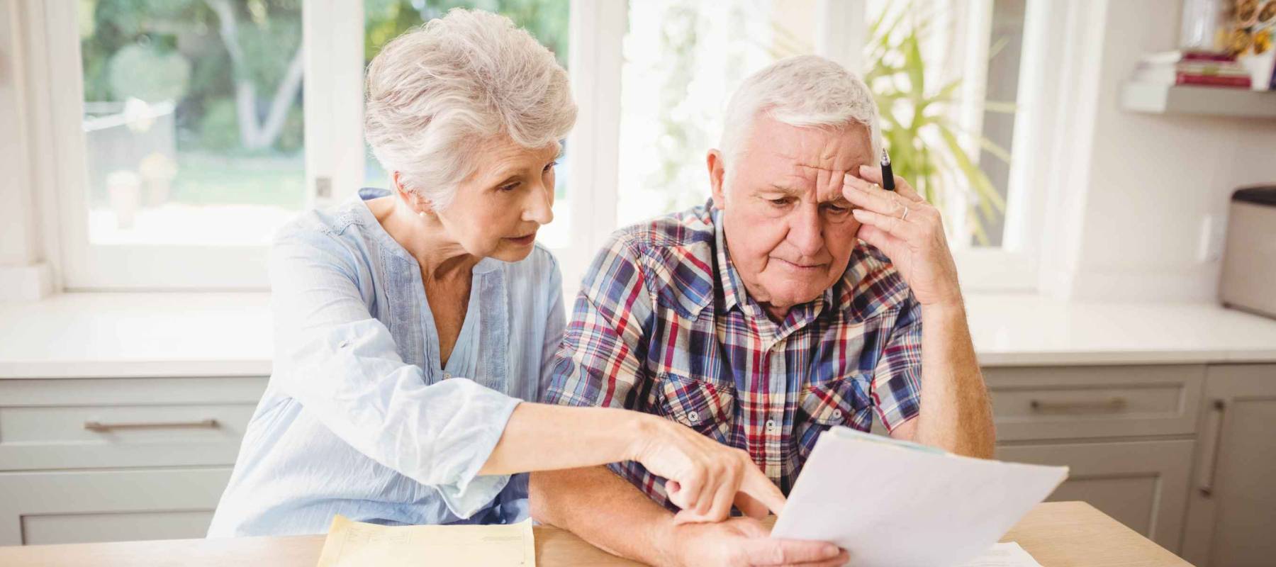 Worried senior couple checking their bills at home