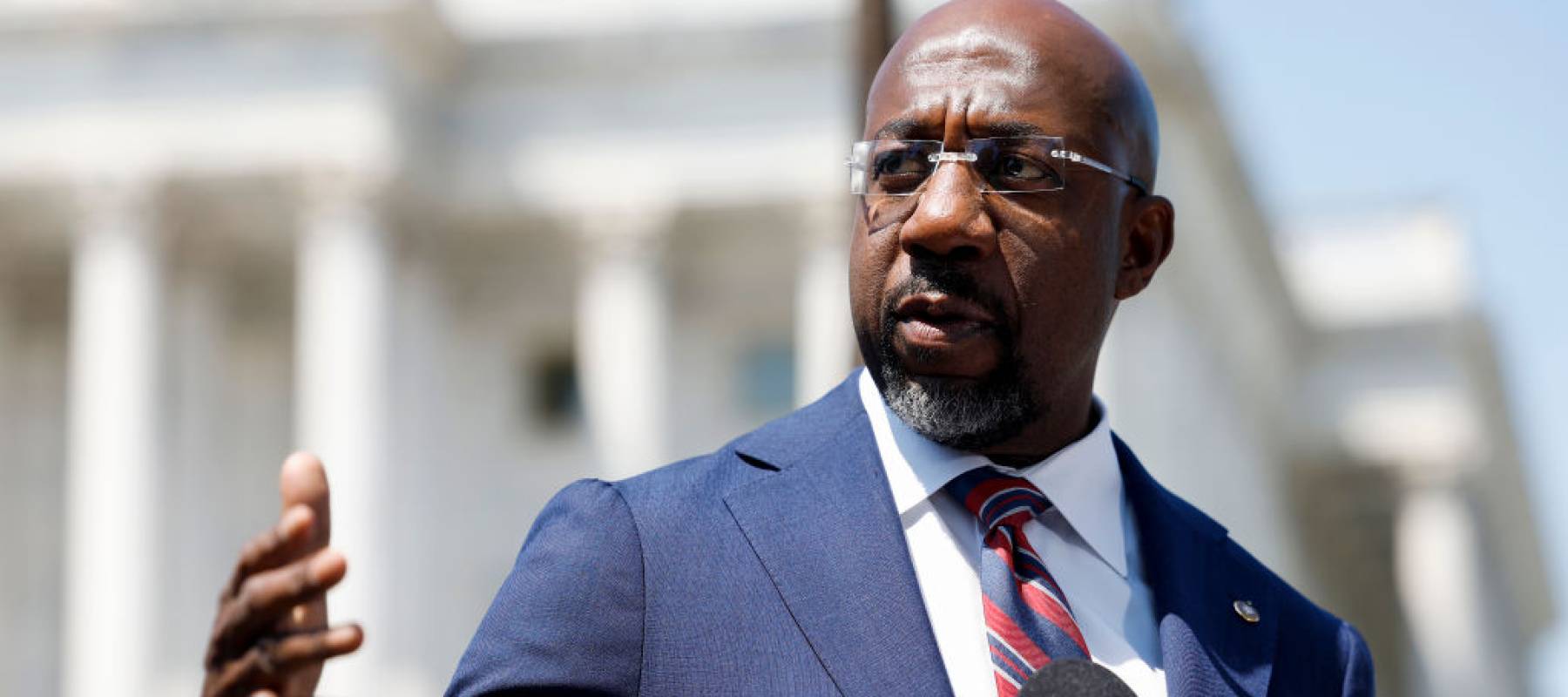 Raphael Warnock speaks animatedly outside the U.S. Capitol building.