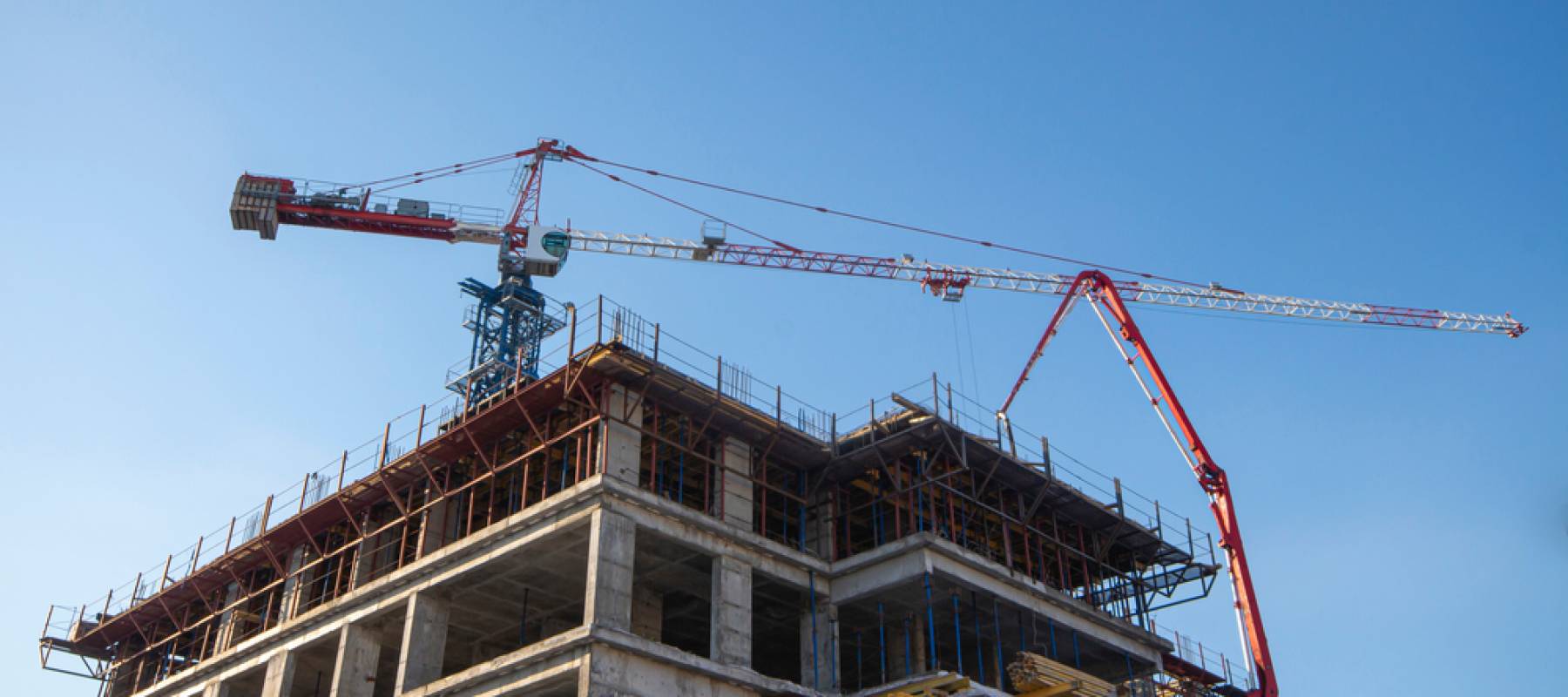 Construction with a crane of a residential multi-storey building on a blue sky background.