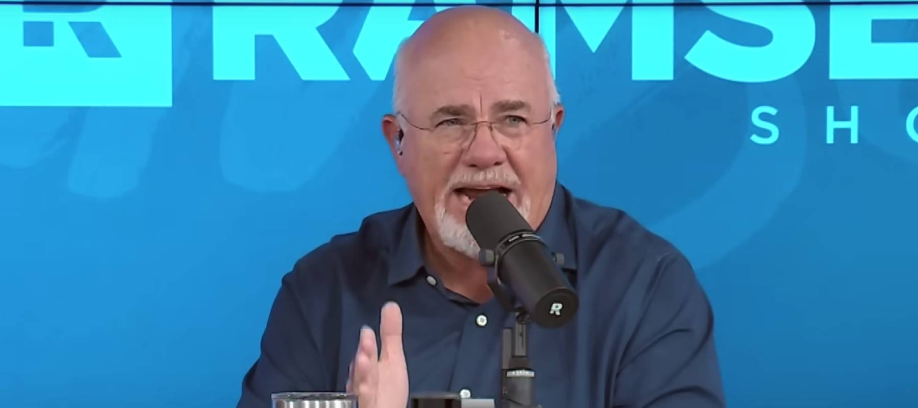 Dave Ramsey looks incredulous as he speaks into a microphone on the set of his radio show.