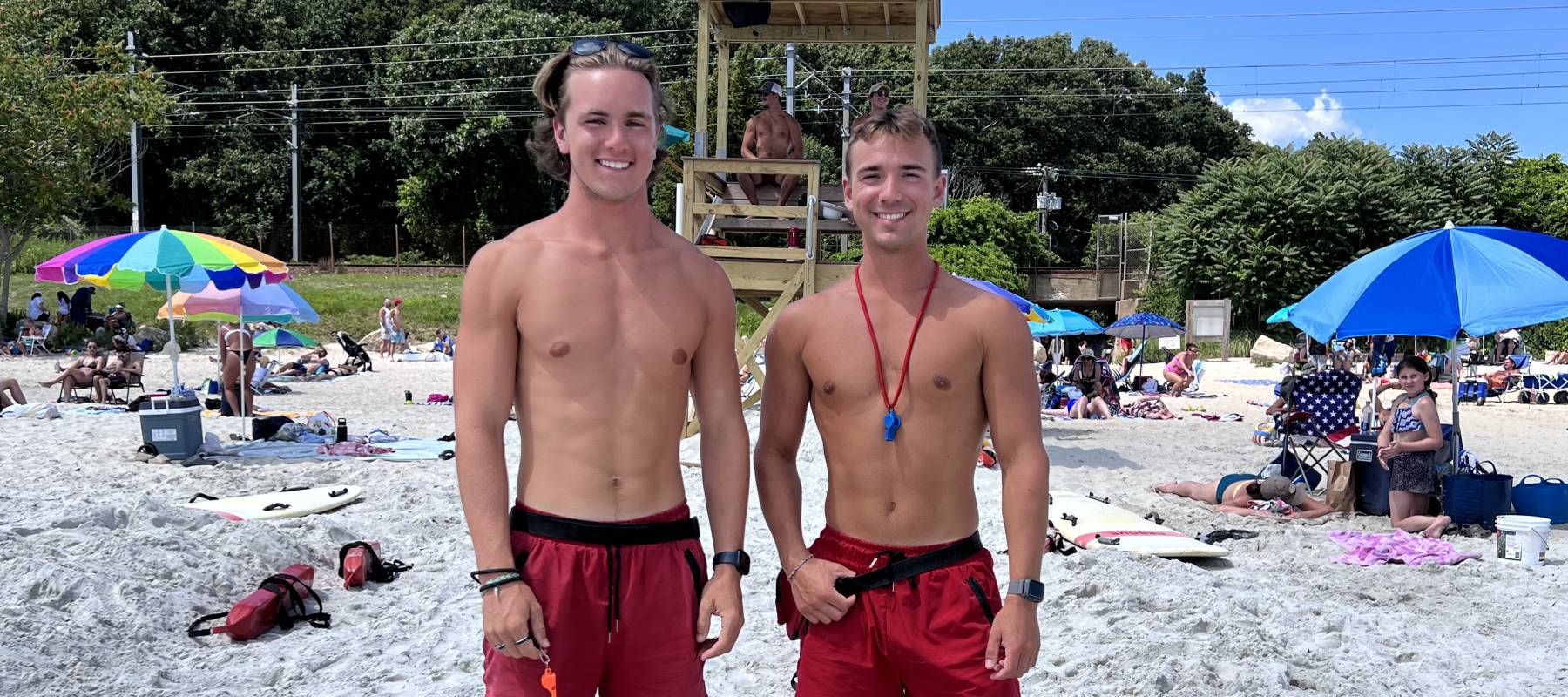 Two teen lifeguards smiling standing on a beach