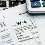 past tax return paperwork w9 w4 1040 with calculator laptop and glasses