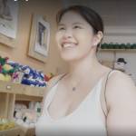 Happy young woman smiles at camera while standing in front of pet toys in a store.