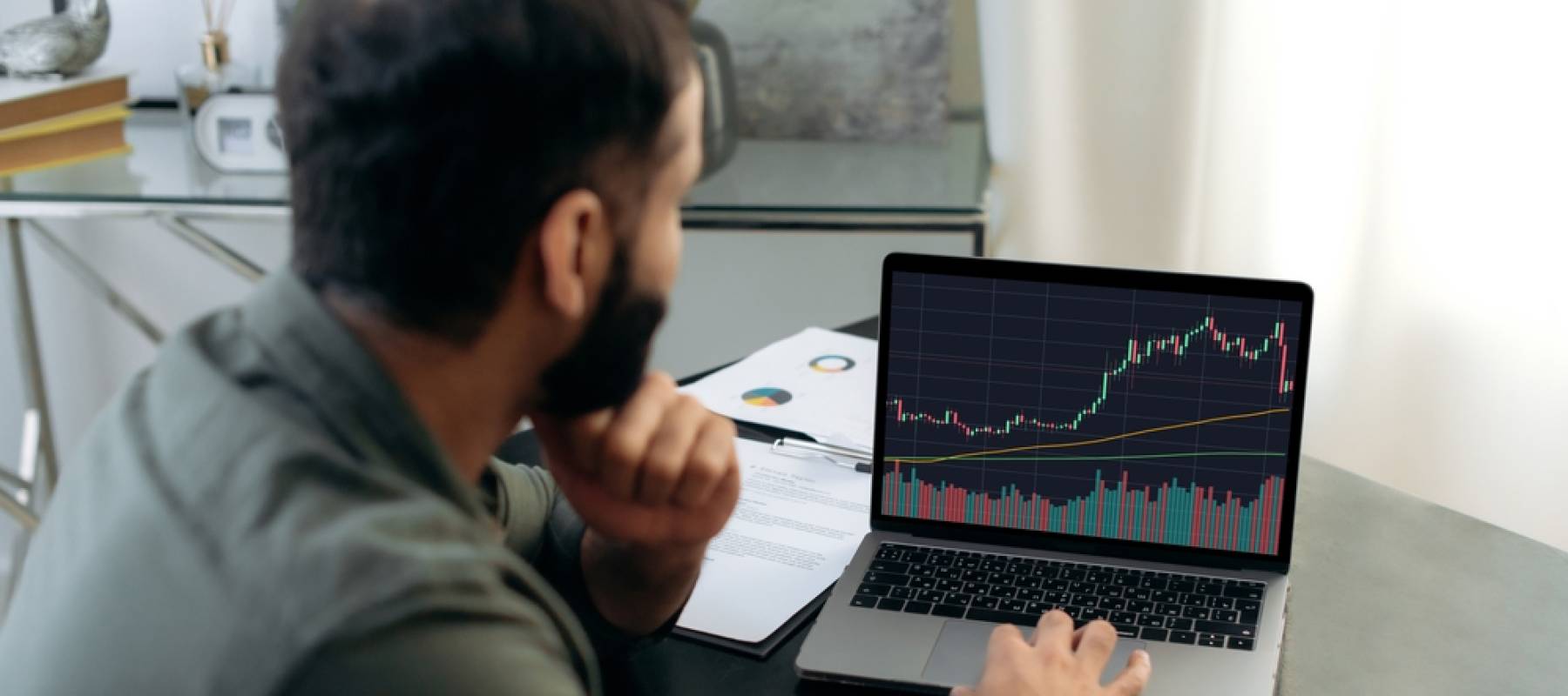 Smart broker investor, uses a laptop to analyze the financial market of cryptocurrencies, invests in e-currency, buys or sells crypto coins, analyzes financial data, predicts stock market