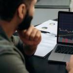 Smart broker investor, uses a laptop to analyze the financial market of cryptocurrencies, invests in e-currency, buys or sells crypto coins, analyzes financial data, predicts stock market