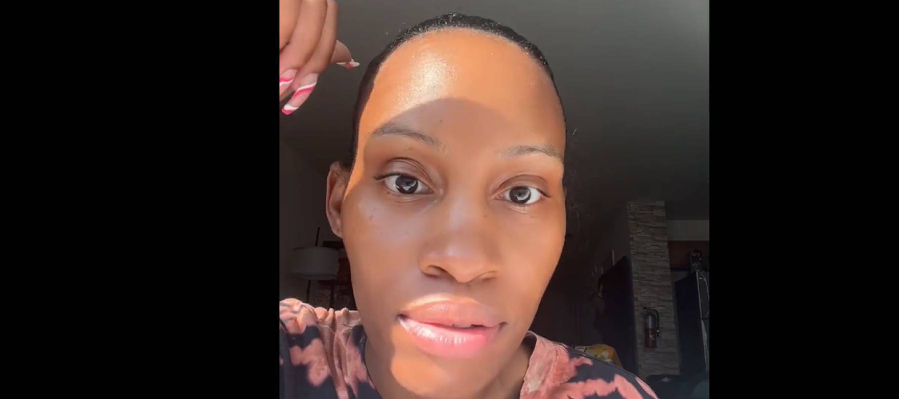 Woman looking dead-on at camera with her hand held up above her head, in the middle of a serious chat.