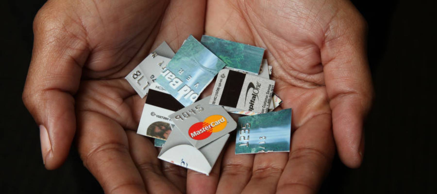 Two hands cupped together holding cut up pieces of multiple credit cards