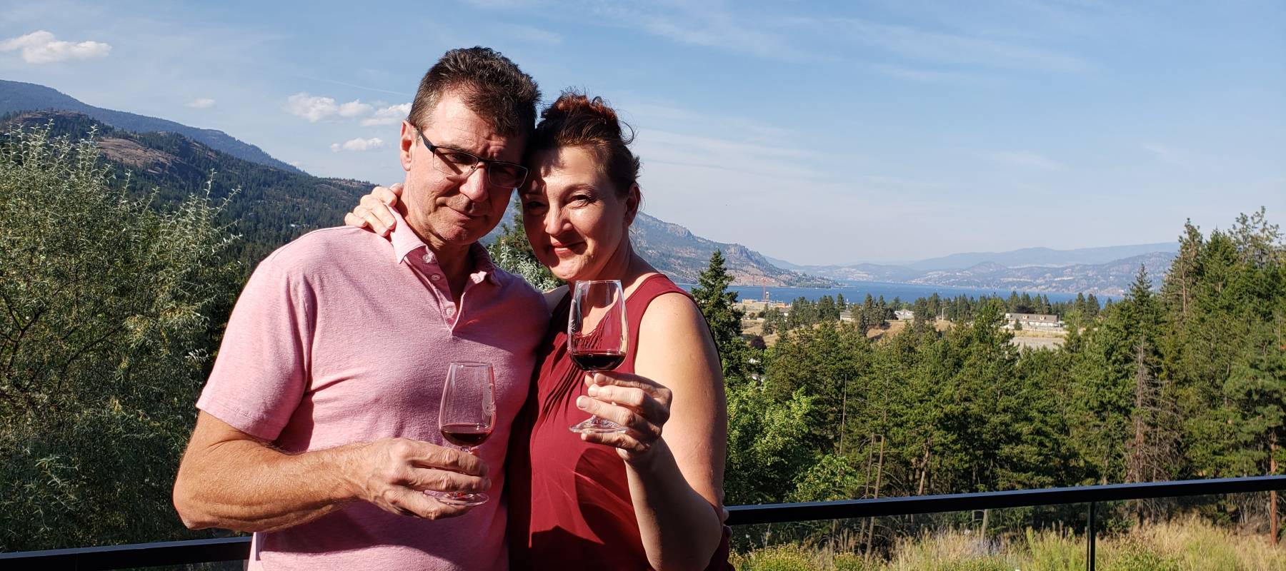 Older couple in late fifties traveling and enjoying outdoors with a glass of wine.