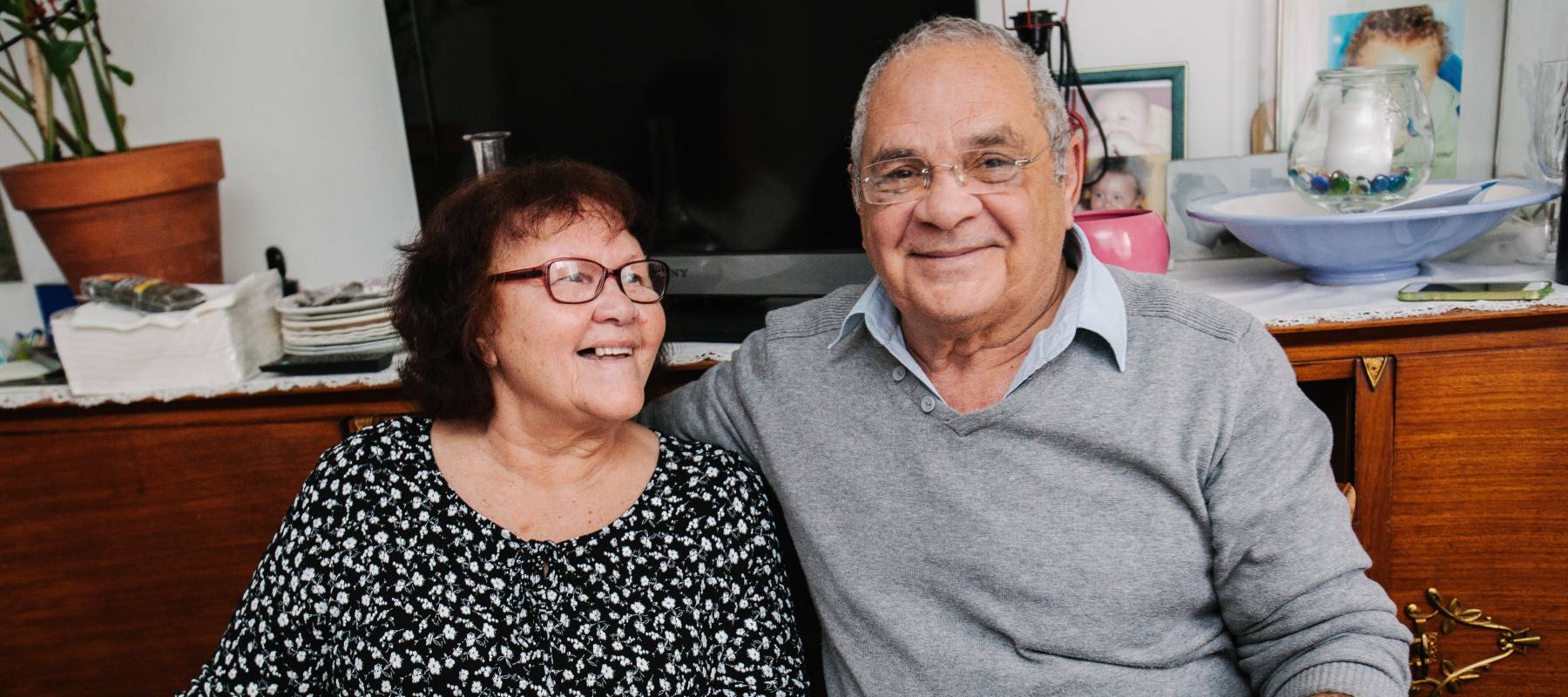 Happy older couple sitting at a dining room table, smiling for the camera.