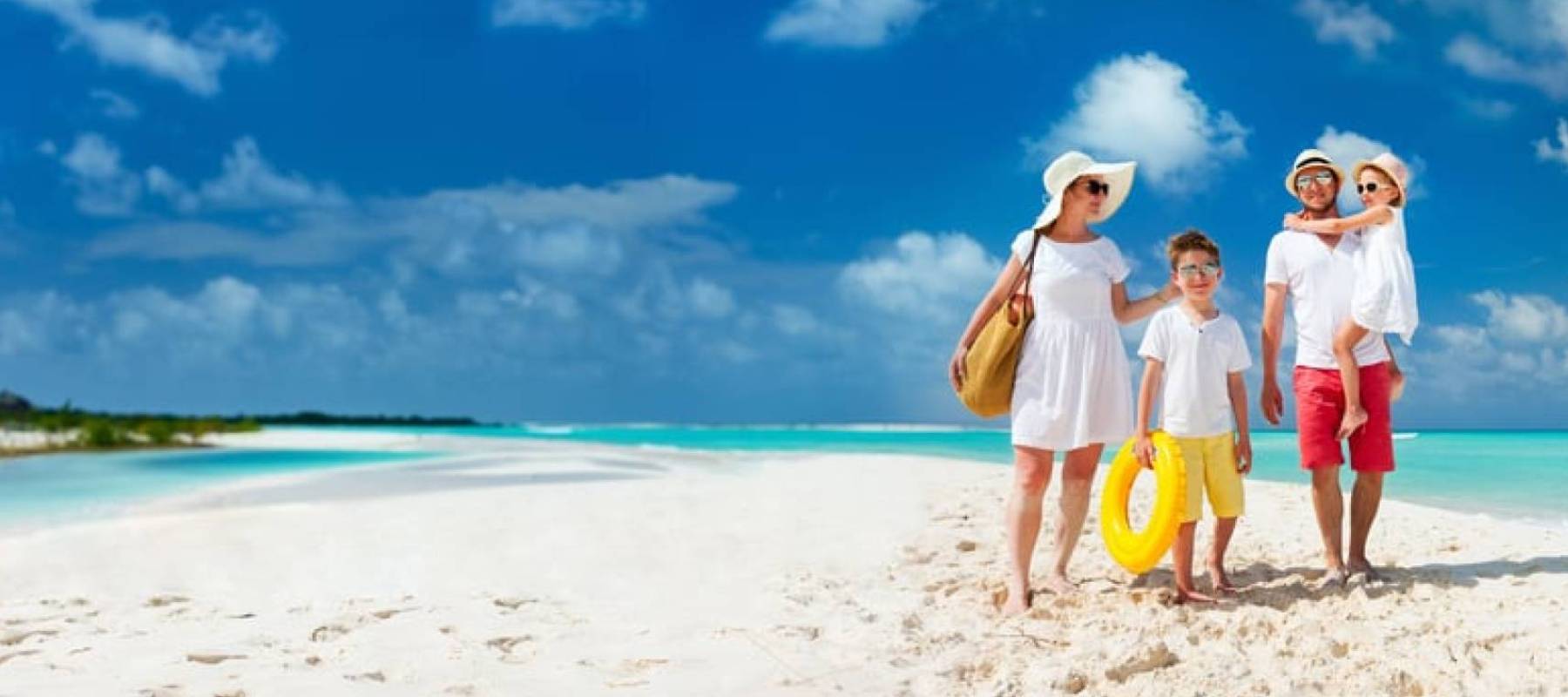 A happy family of four walks along a pristine beach.