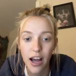 Young woman looking directly at the camera with her mouth open, speaking.